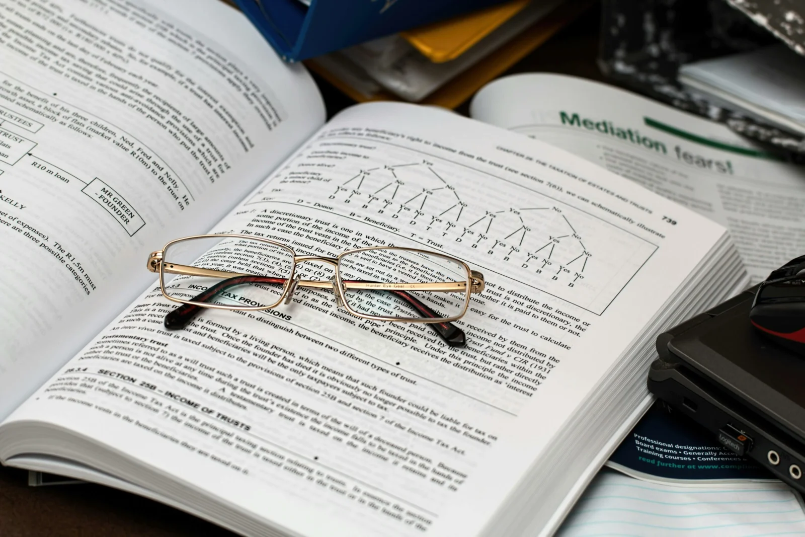 Aluno pesquisando para o projeto de extensão com o Livro aberto e óculos em cima dele